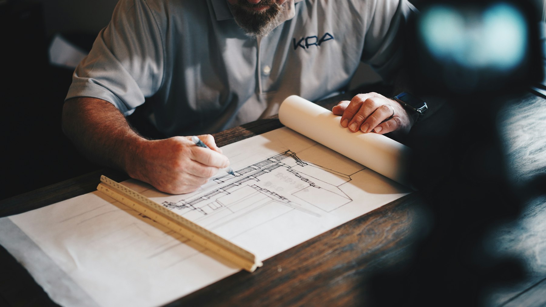 Builder marking up a set of construction drawings on a workbench