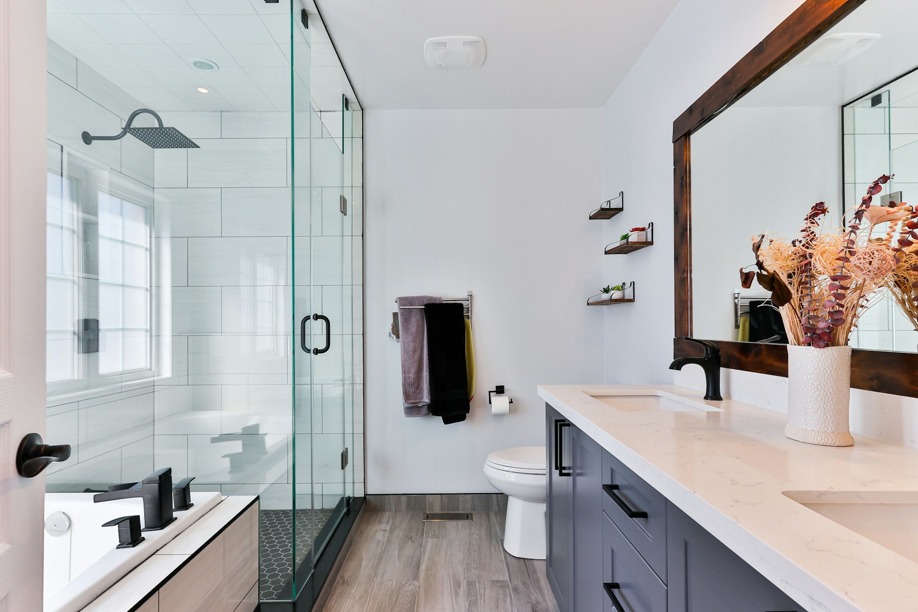 Renovated bathroom with a glass shower enclosure, matte black fittings and a framed mirror