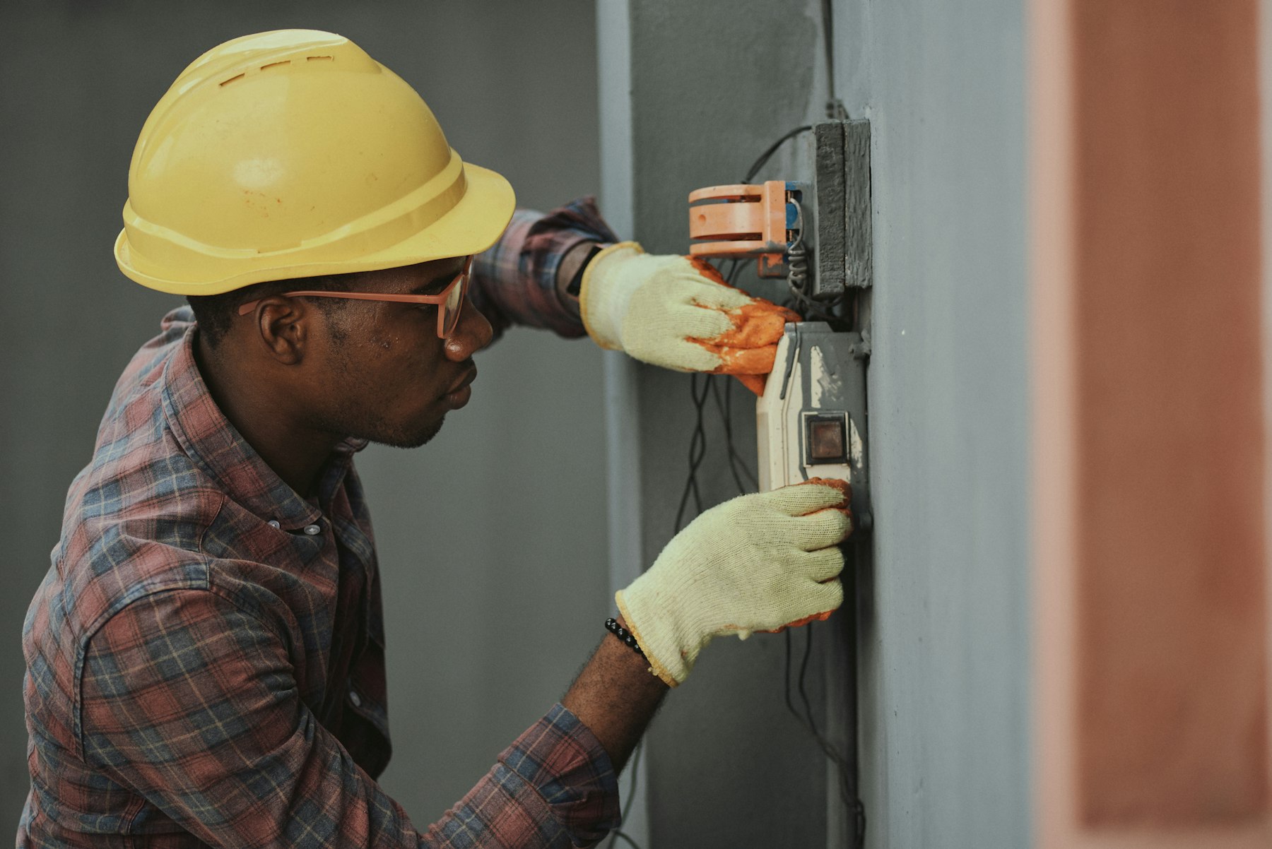 Electrician in a hard hat terminating conductors at a rough-in panel